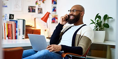 man on laptop while talking on phone