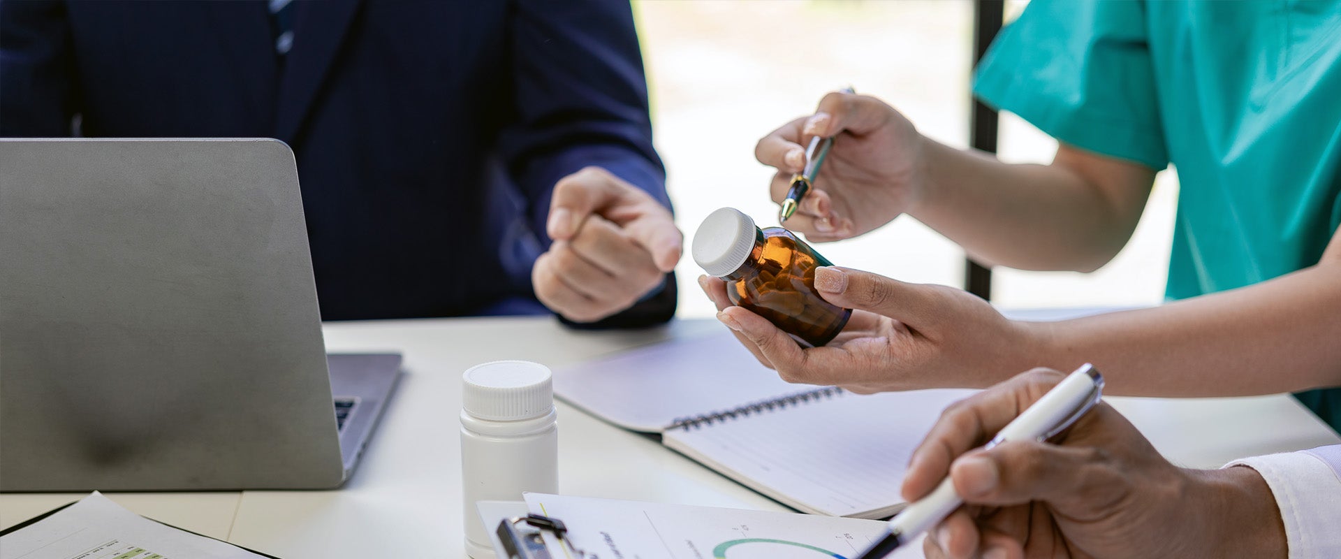 medical professionals writing on pill bottles at table