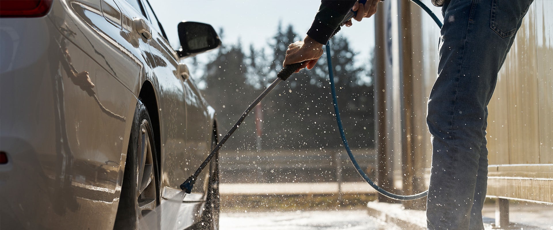 Person washing car in car wash self-service bay