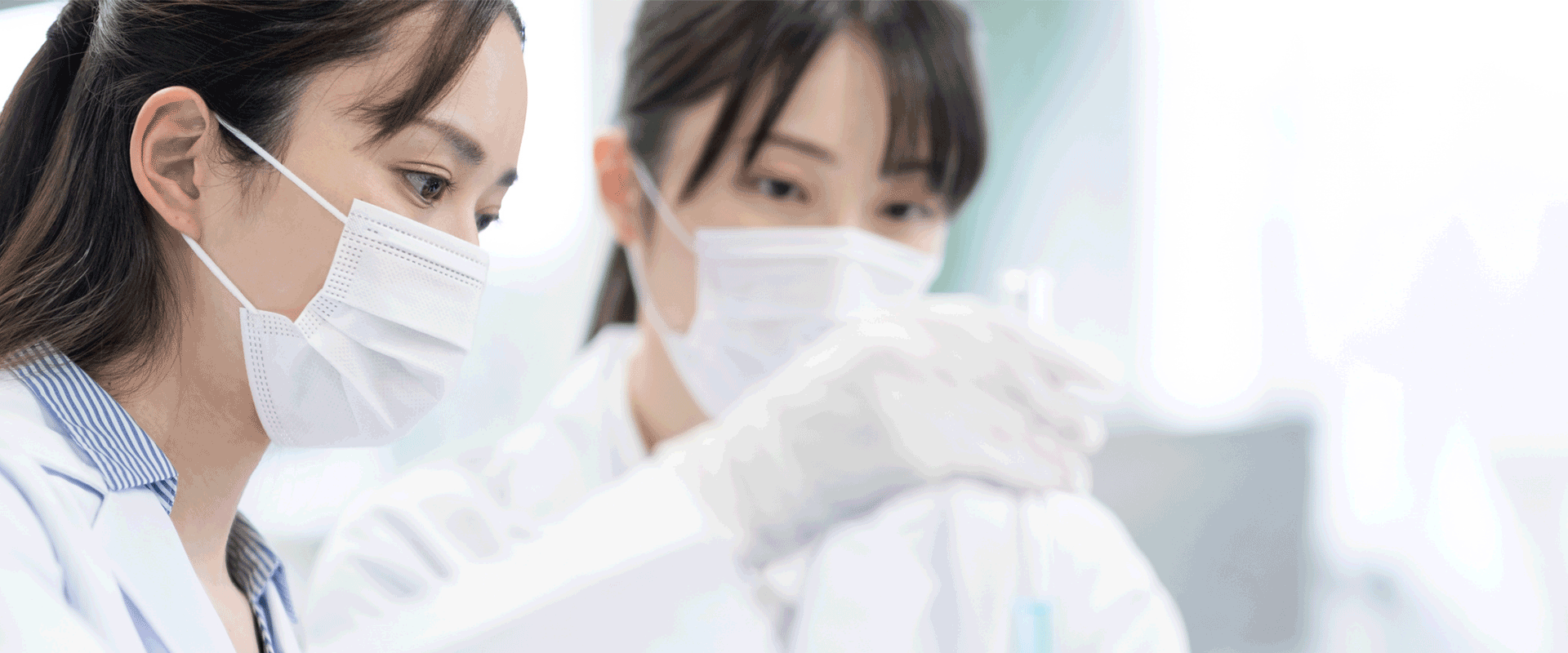 two researchers in white coats with pipette