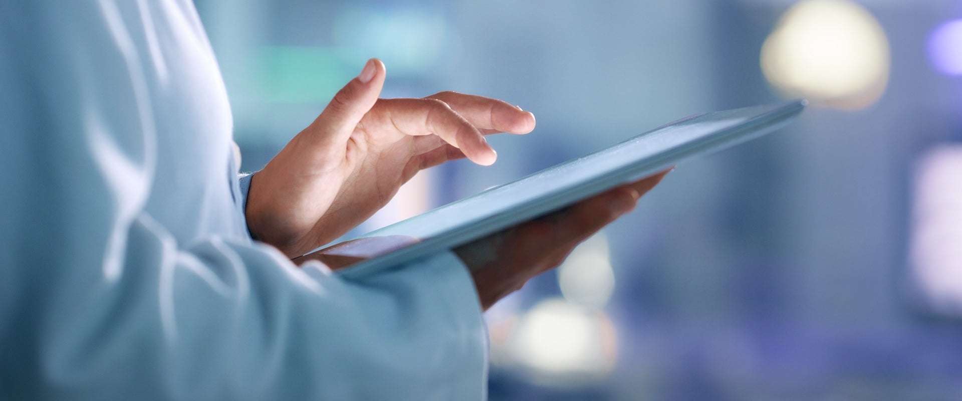 researcher in white coat holding tablet