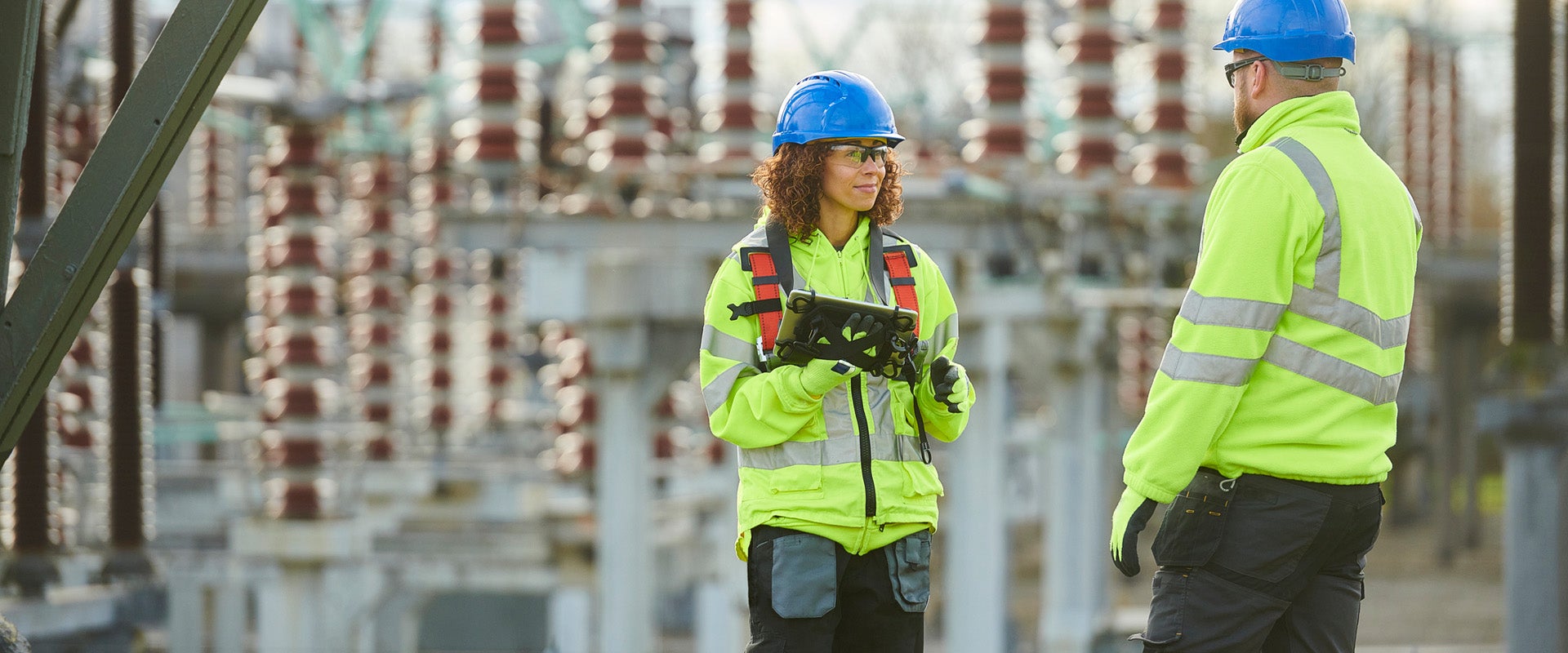 Two colleagues standing and working together at an electrical substation