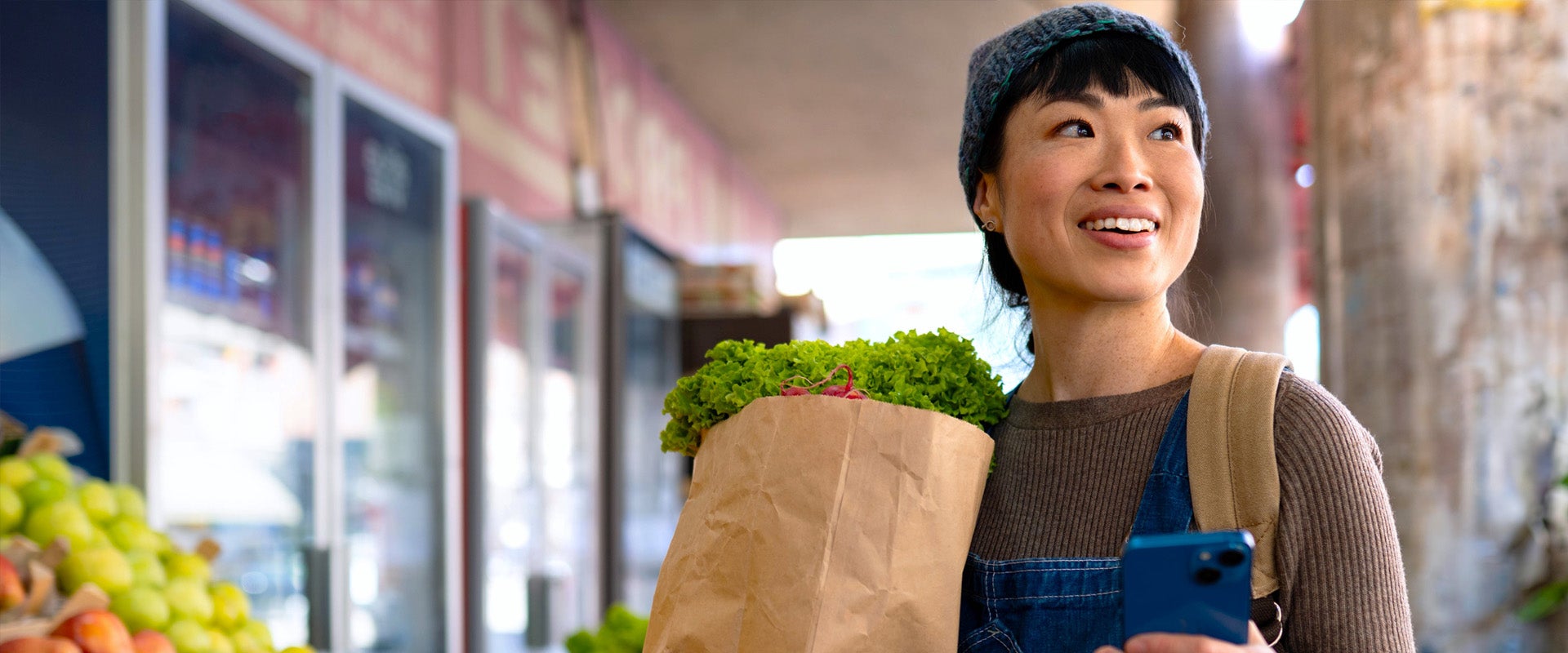 woman holding bag of groceries in grocery store