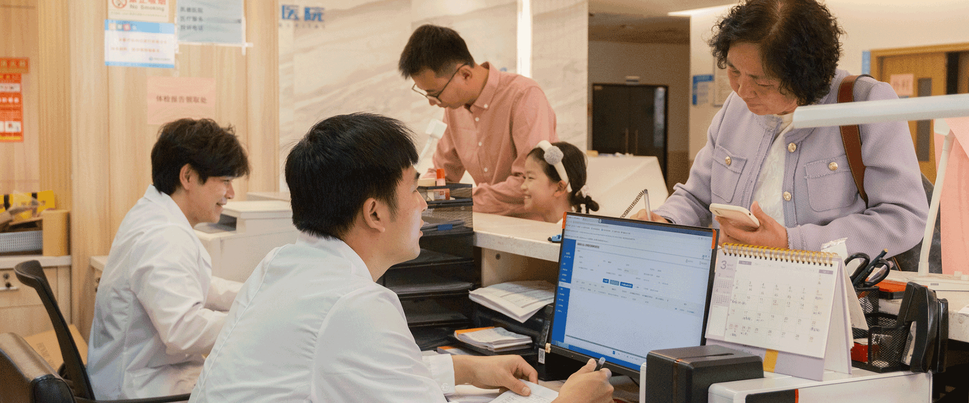 patients reading forms at hospital reception desk