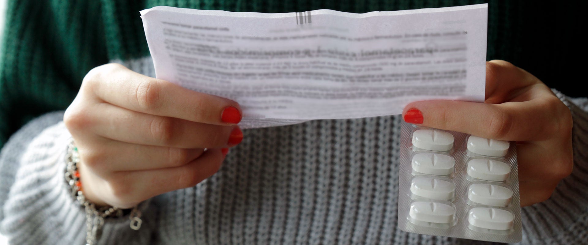 person holding pills and paper