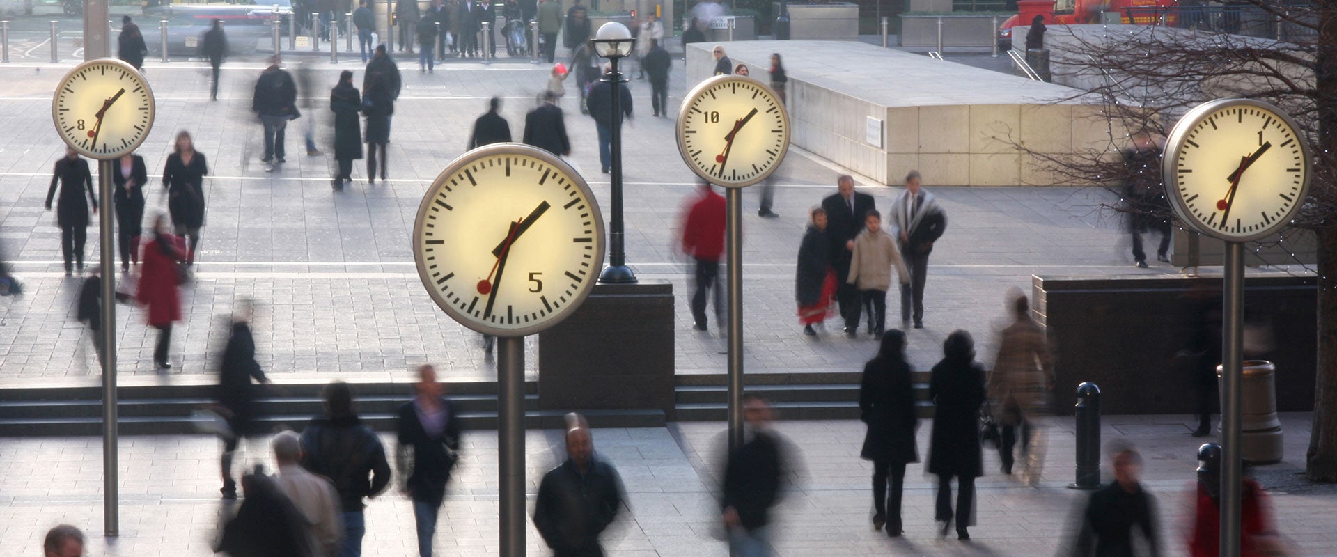 people walking behind clocks