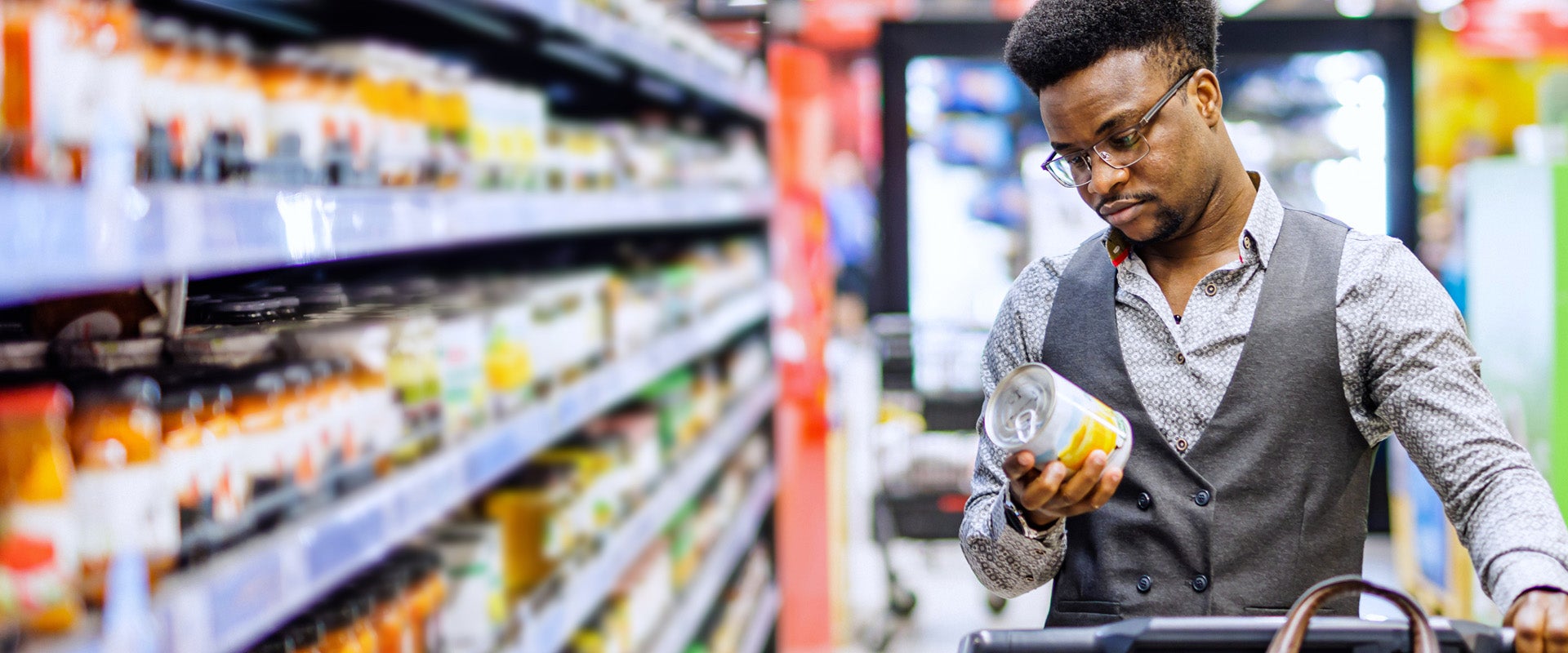 Man standing in grocery store looking at label on can of food