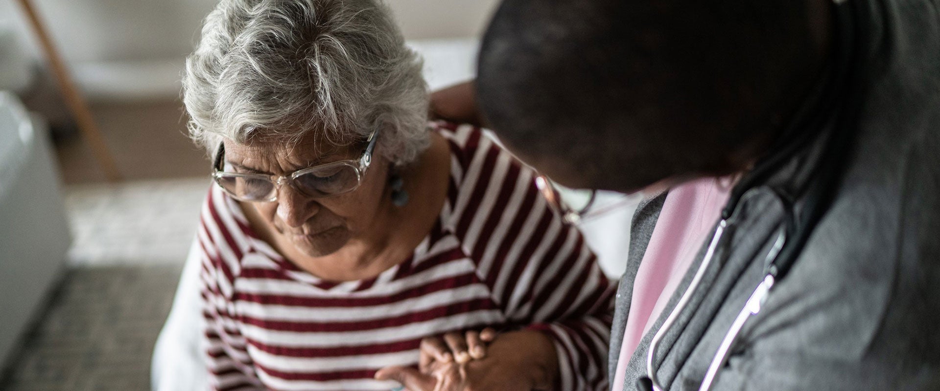 caretaker holding elderly woman's hand