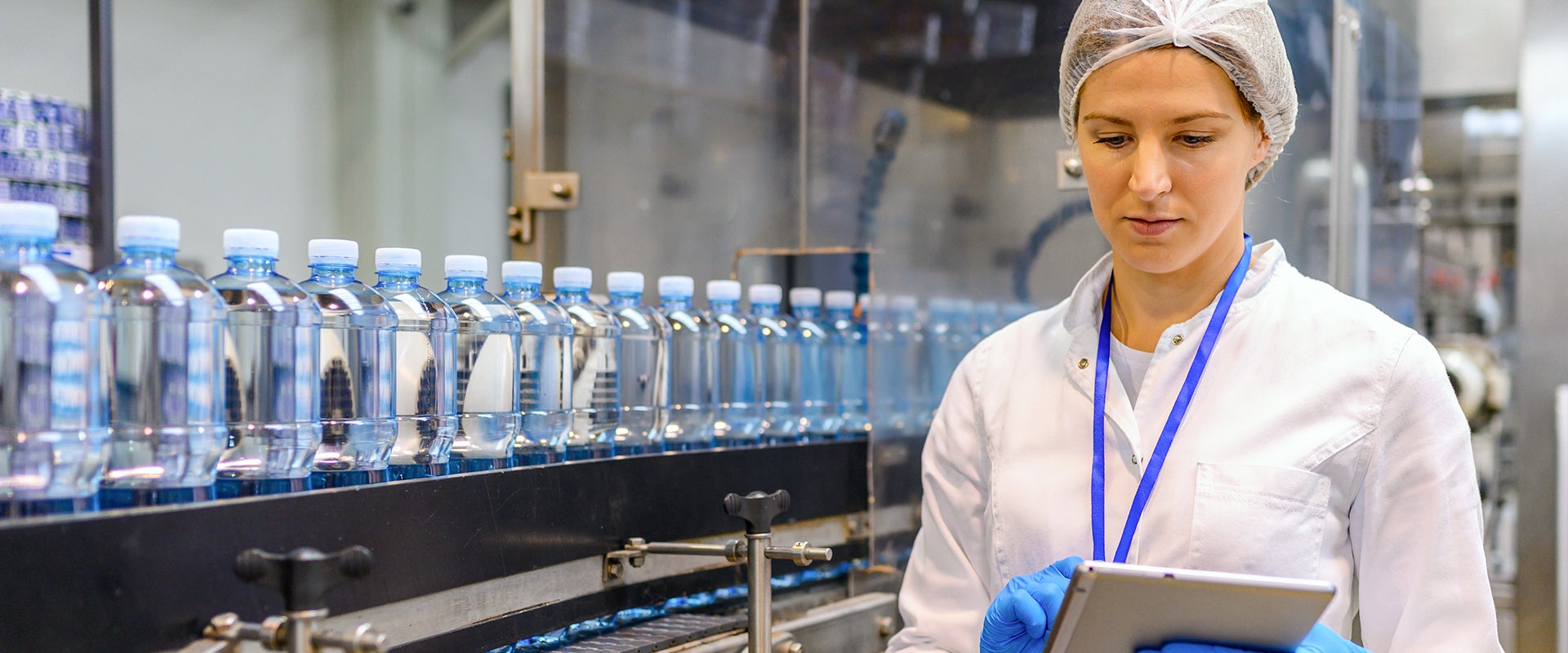 worker next to water bottles on conveyor belt