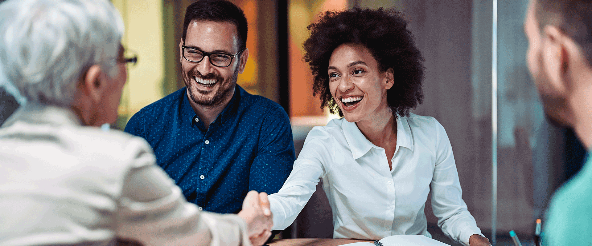 four people in business meeting shaking hands