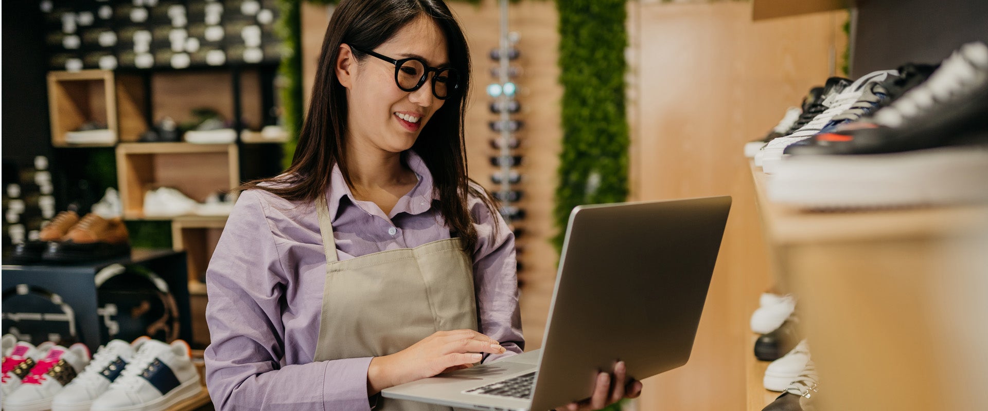 Shop owner checking footwear inventory on laptop