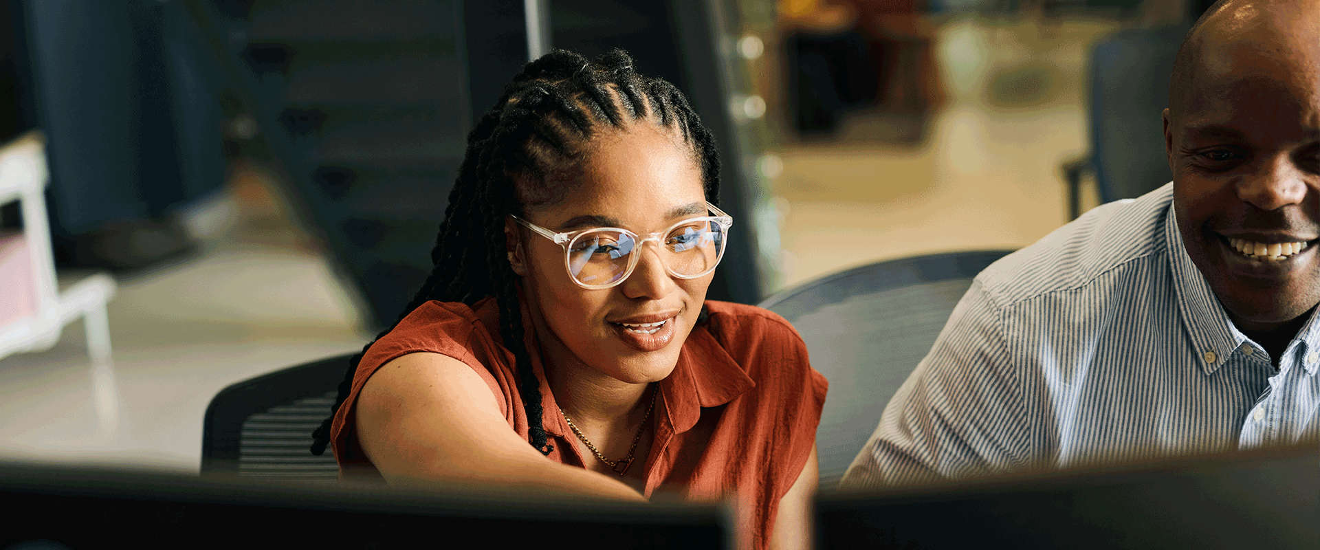 woman smiling next to man in front of computer monitors
