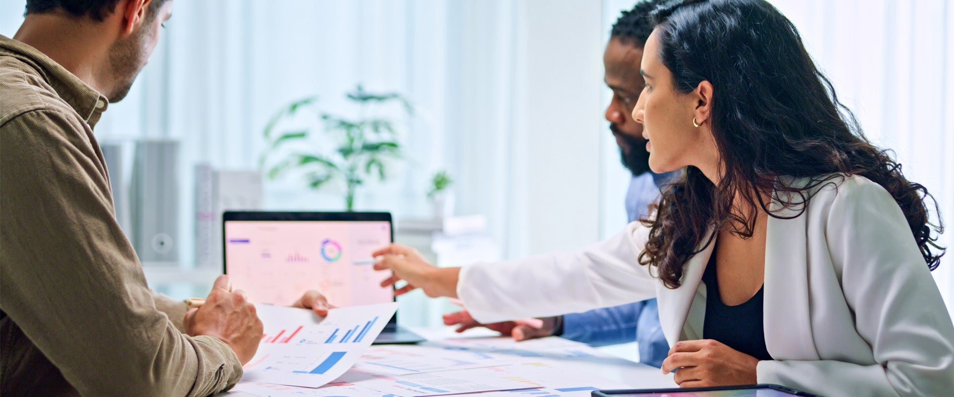 Three people sitting at a table reviewing information on a laptop