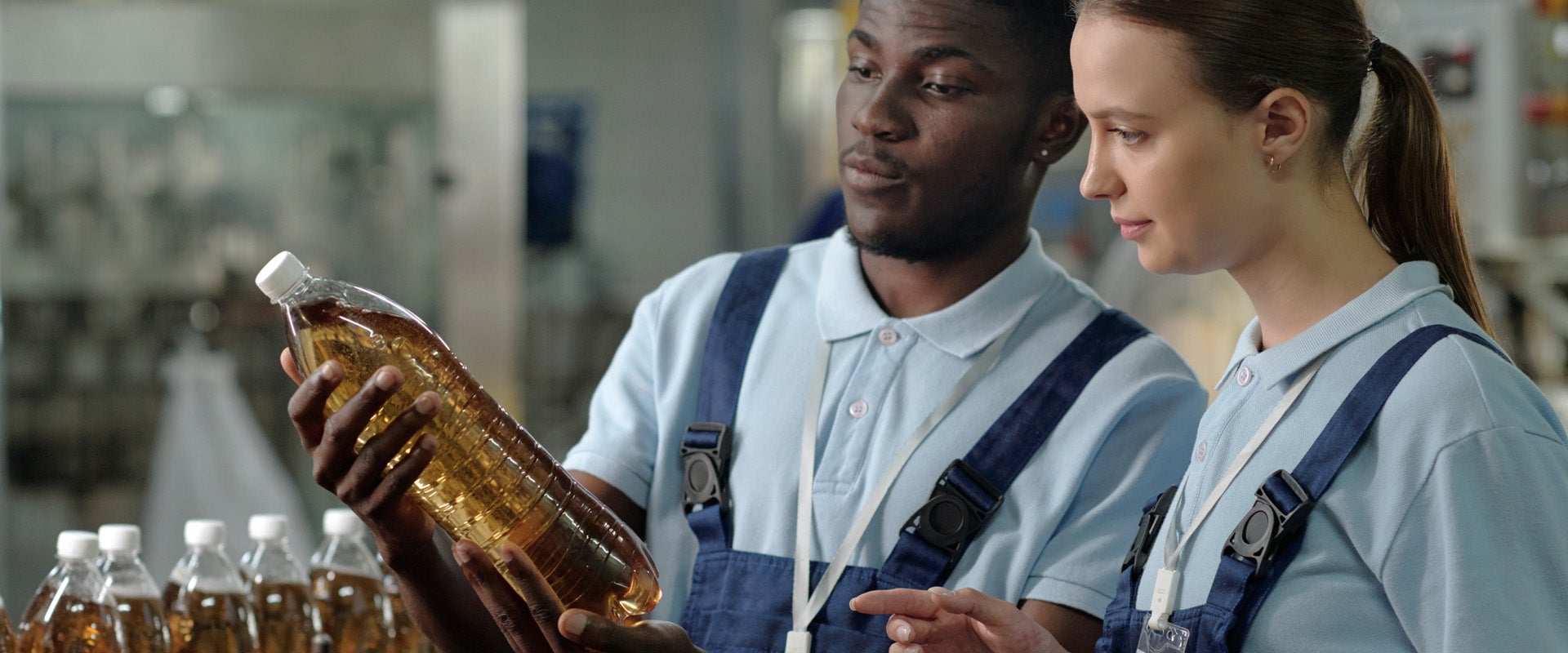 Two bottling plant workers inspecting bottle