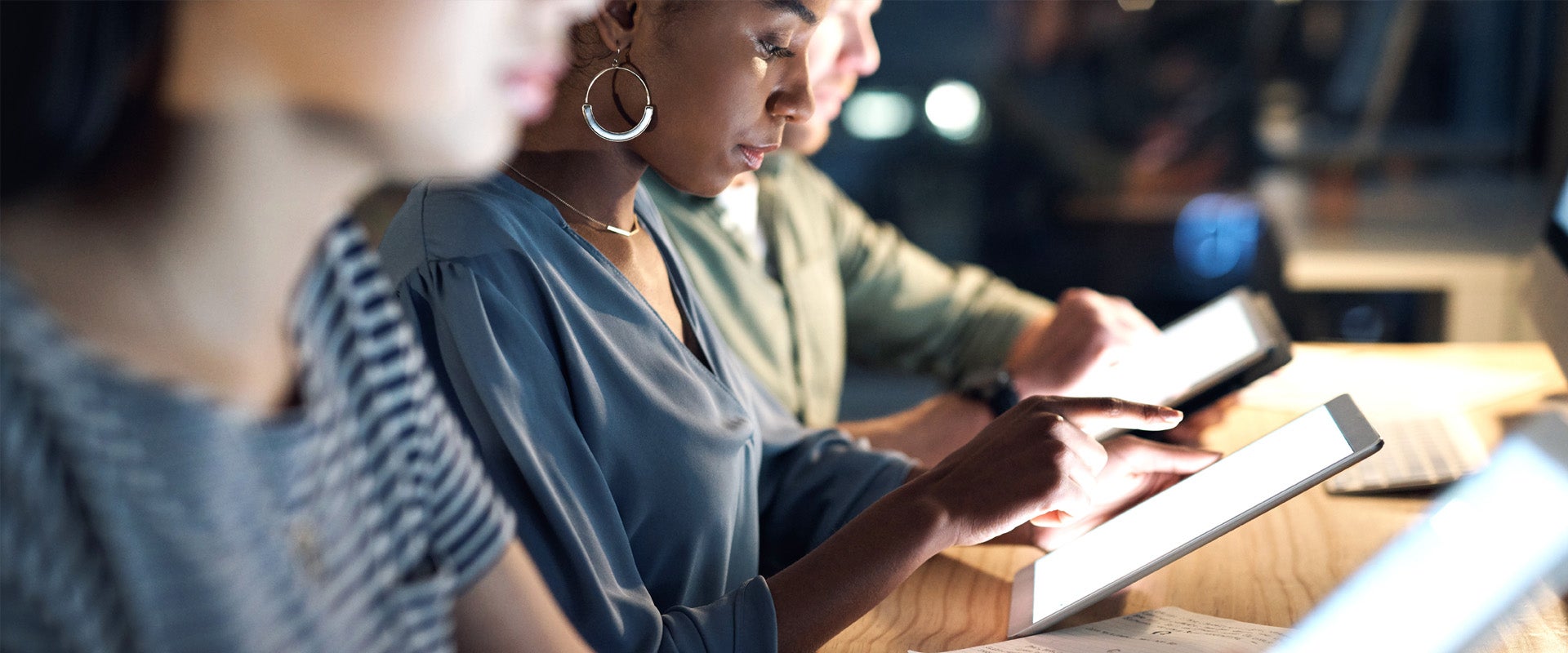 People sitting at bench working on tablets