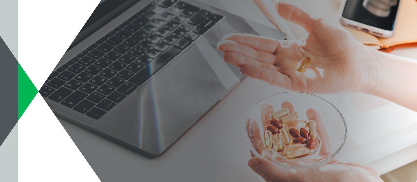 hands holding supplements over laptop